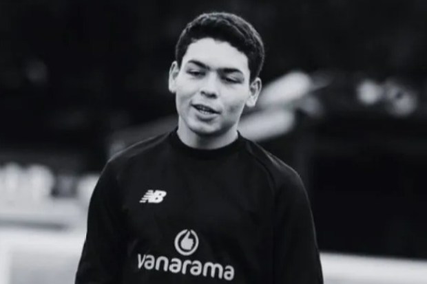 Black and white photo of a young man wearing a black sweatshirt with a logo.