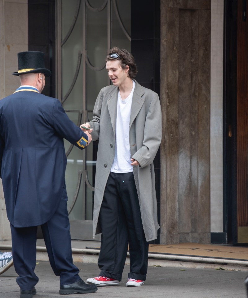 Cruz Beckham accepting something from a doorman.
