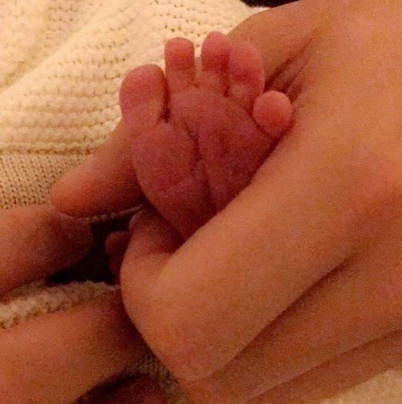 A newborn baby's foot held in an adult's hand.