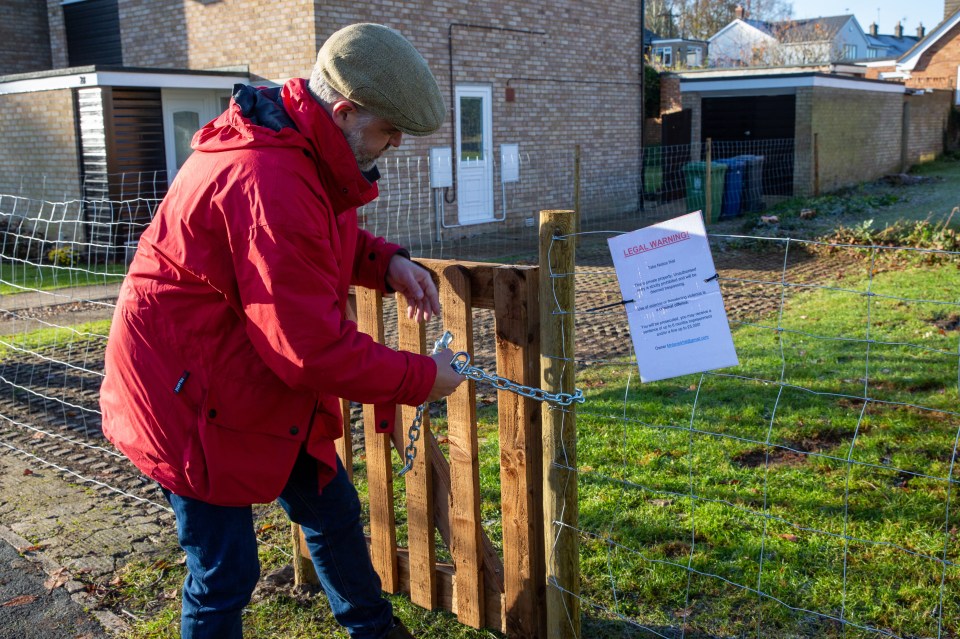 Man securing a gate with a chain and lock.