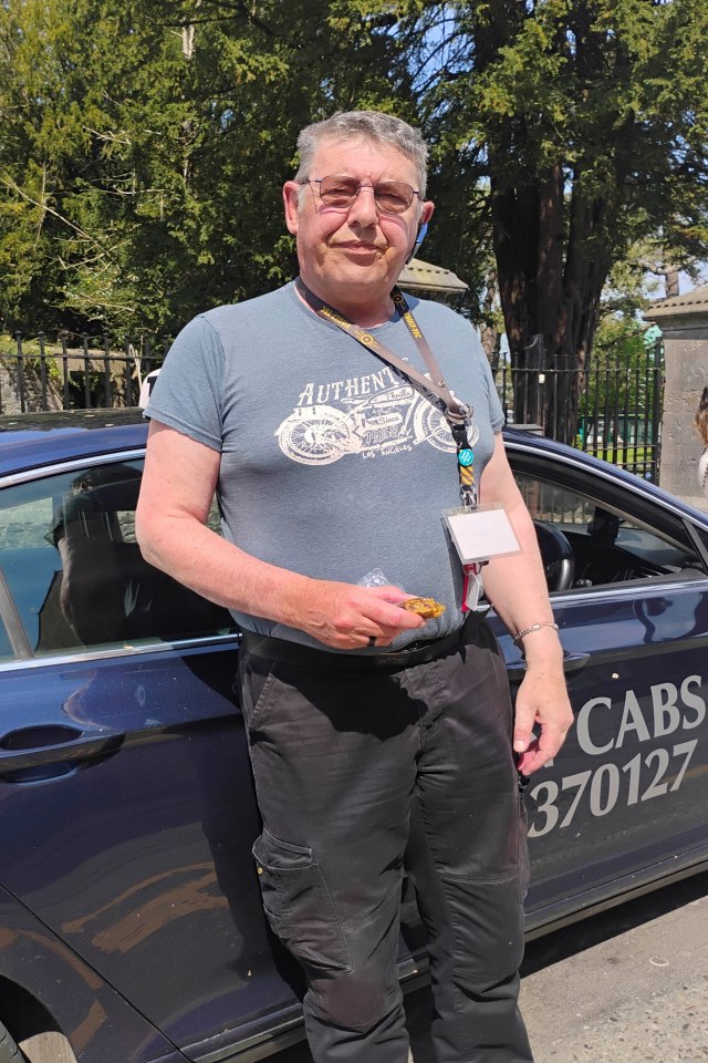A taxi driver standing next to his cab.