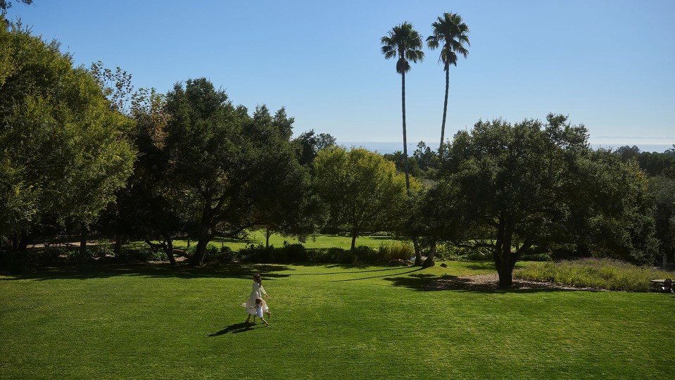 Woman and child walking on a grassy lawn.