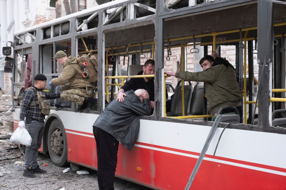 Man crying at a destroyed trolleybus after a missile strike.