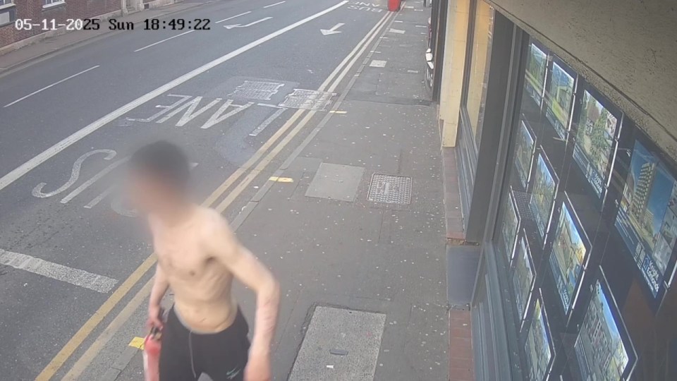 Surveillance image of a shirtless man carrying a fire extinguisher.