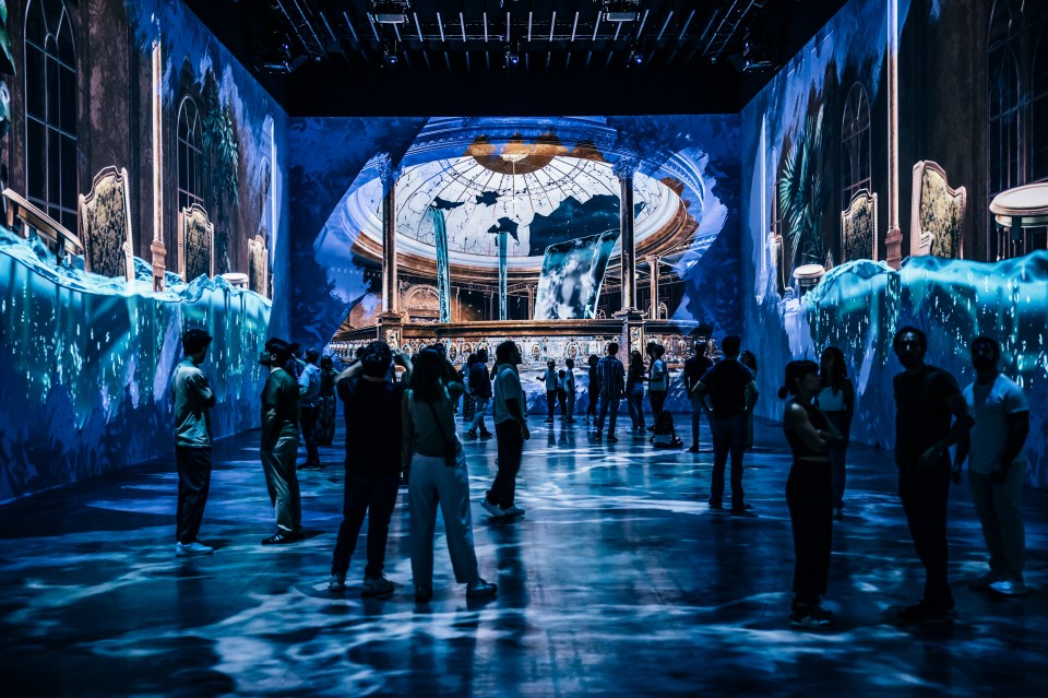 People viewing a Titanic exhibition featuring immersive projections of the ship's interior.