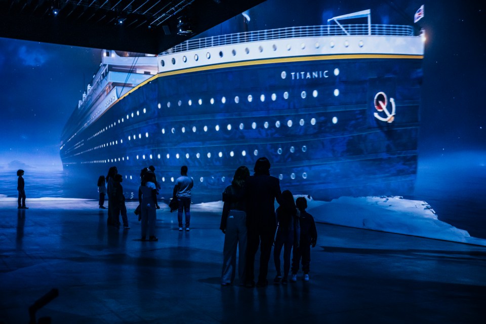 People viewing a large projection of the Titanic.