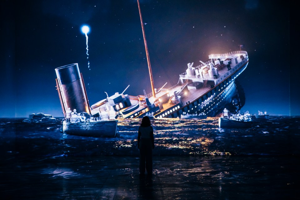 A person stands before a large projection of the Titanic sinking.