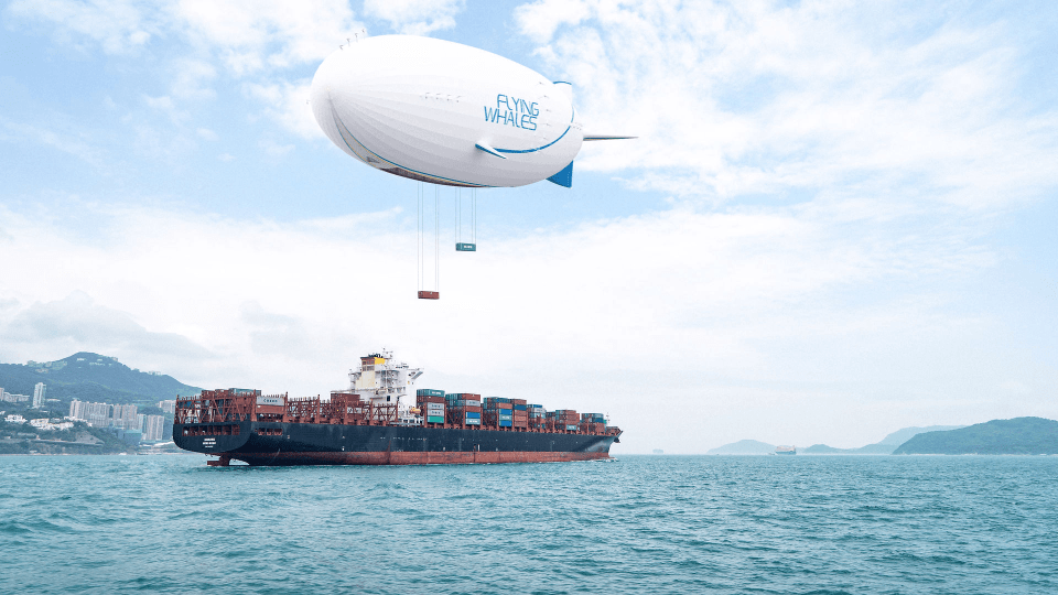 Flying Whales airship delivering cargo containers to a cargo ship at sea.