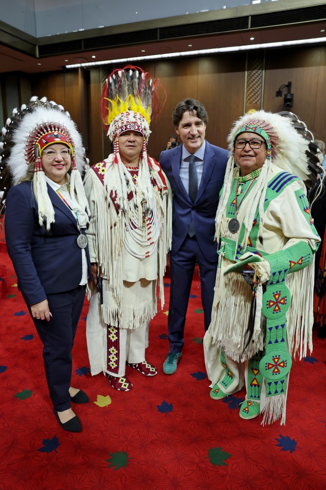 Justin Trudeau with Indigenous peoples in traditional regalia.