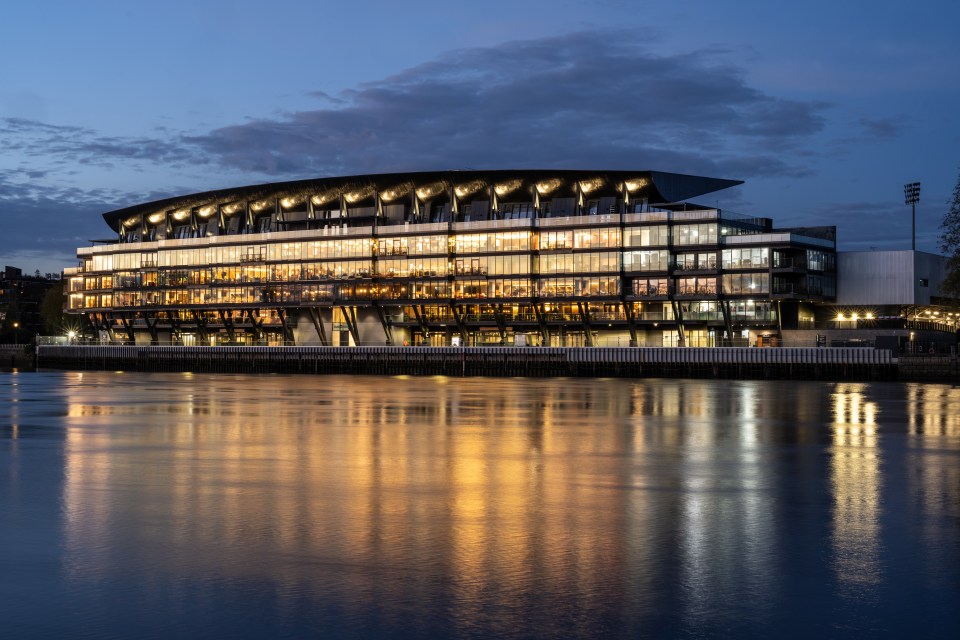 Fulham FC hospitality stand at night, reflected in the water.