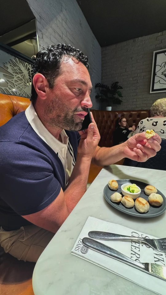 Man on phone eating at restaurant.