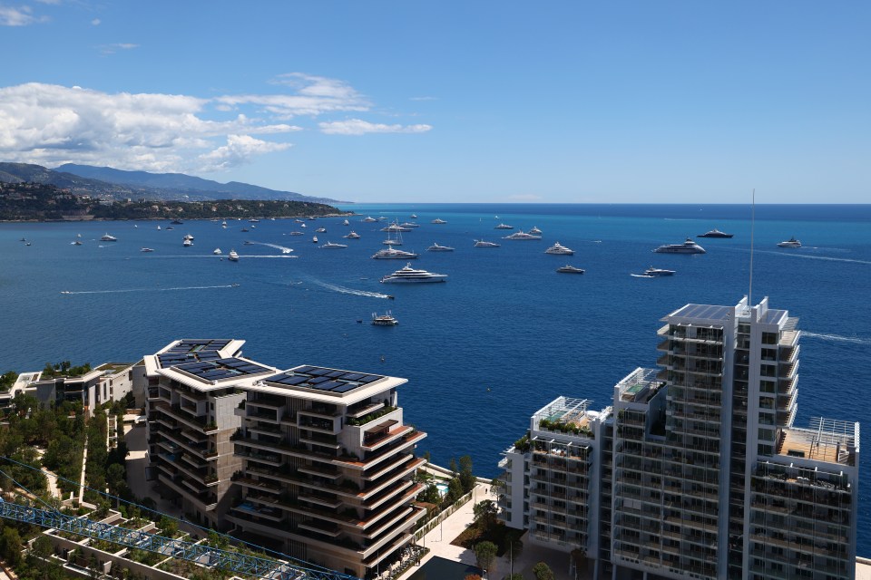 Aerial view of Monaco harbor with numerous yachts and modern buildings.