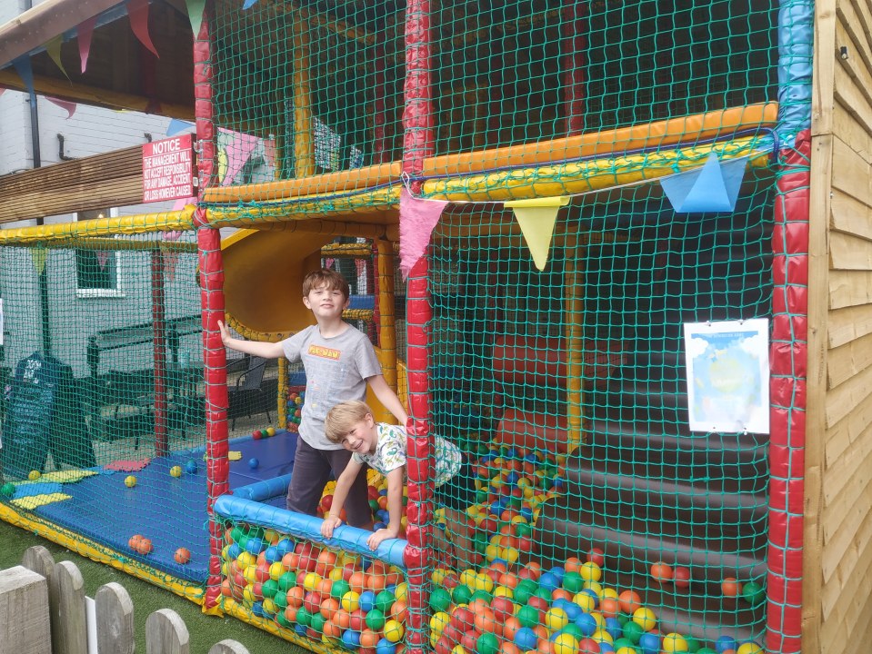 Two boys playing in a ball pit.