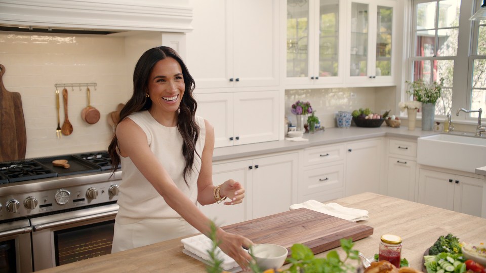 Meghan Markle in a white top in her kitchen.
