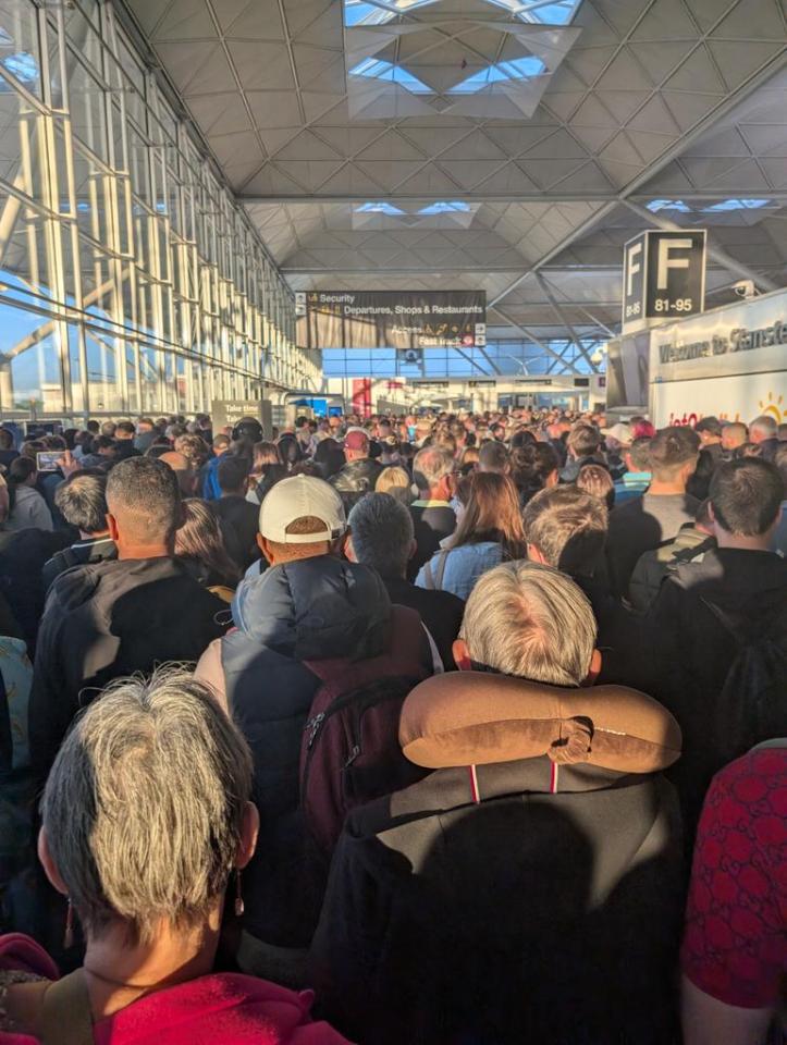 Crowded airport terminal with passengers waiting.
