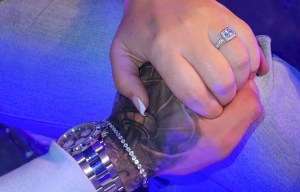 Close-up of an engaged couple holding hands, showcasing an engagement ring.