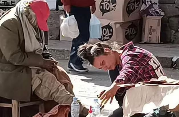 A young woman assisting a homeless man.