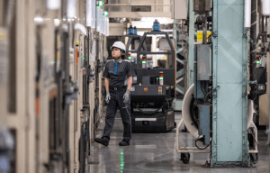 Factory worker standing in an aisle between industrial machinery.