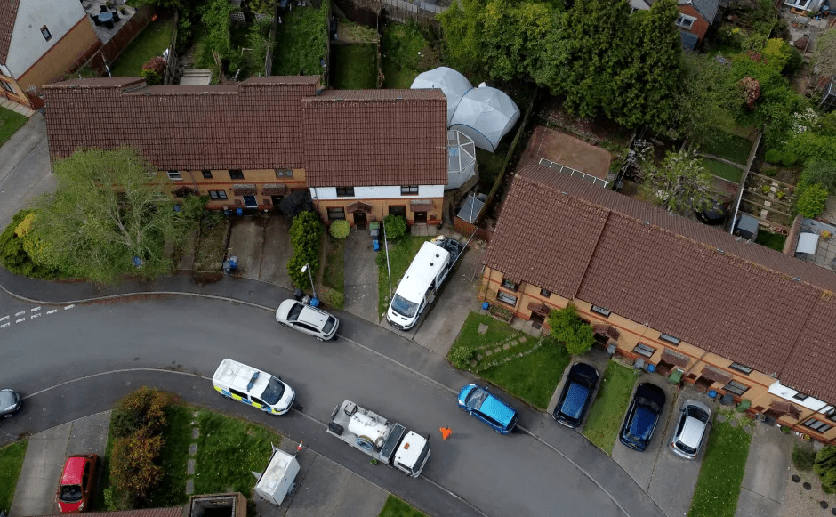 Aerial view of a residential street with parked cars and emergency vehicles.
