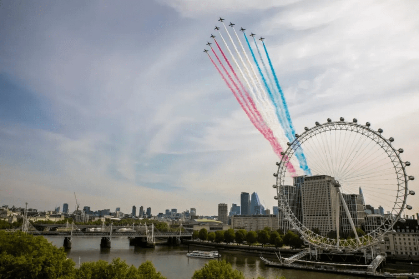 Jets leaving red, white, and blue smoke trails over the London Eye.