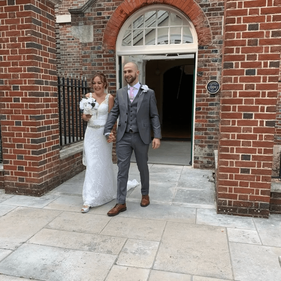 Newlyweds leaving a brick building.