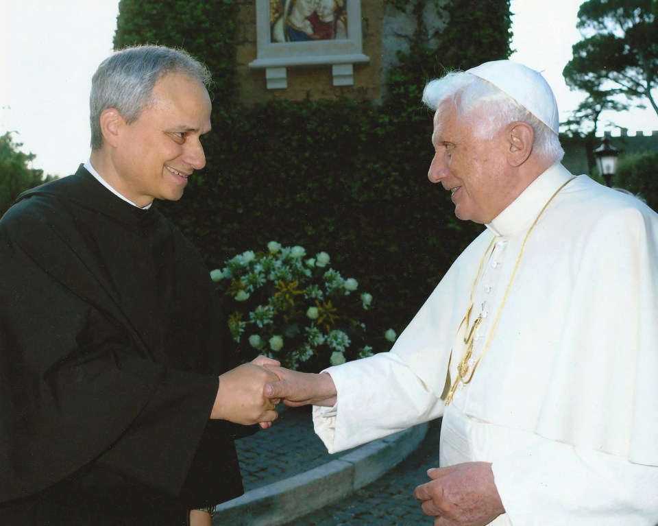 Pope Benedict XVI shaking hands with a priest.