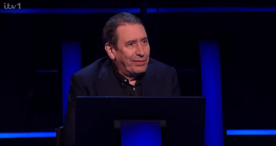 Man sitting at a game show podium.