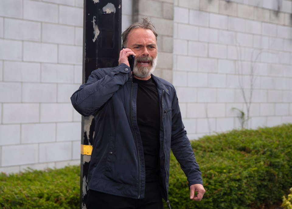 A man on a cell phone, appearing distressed.
