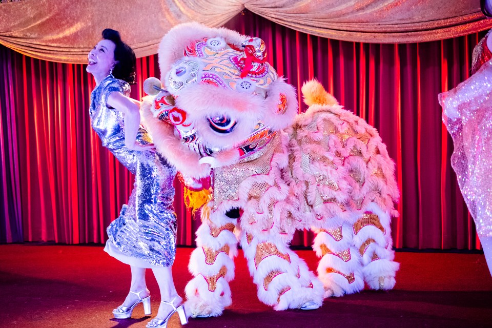 Joan Chen in a silver sequined dress with a lion dance costume.
