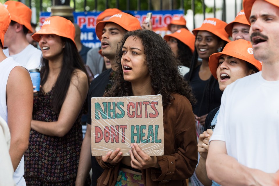 Junior doctors rally outside Downing Street, holding a sign that reads "NHS cuts don't heal."