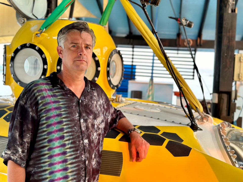 Man standing by yellow submersible.