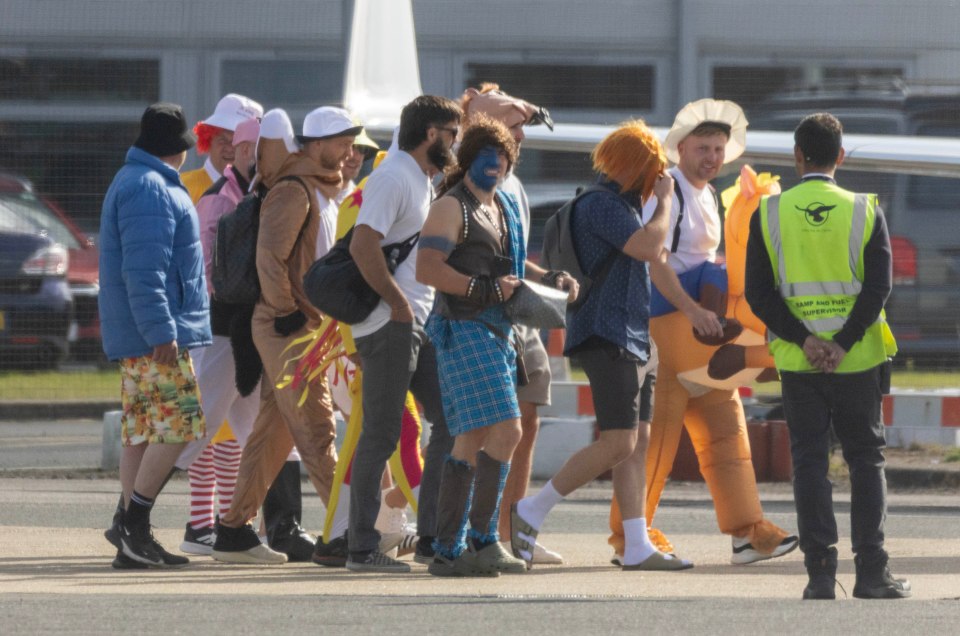 A group of men in various costumes boarding a private jet.