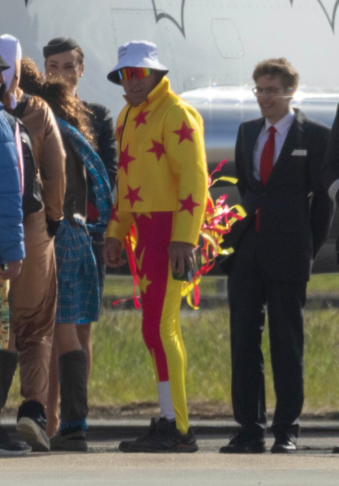 A group of men in various costumes boarding a private jet.
