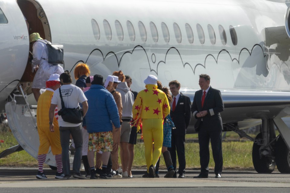 A group of men in various costumes boarding a private jet.