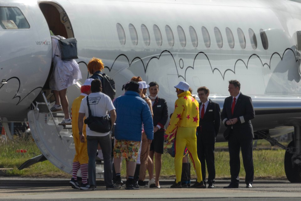 Men in various costumes boarding a private jet.