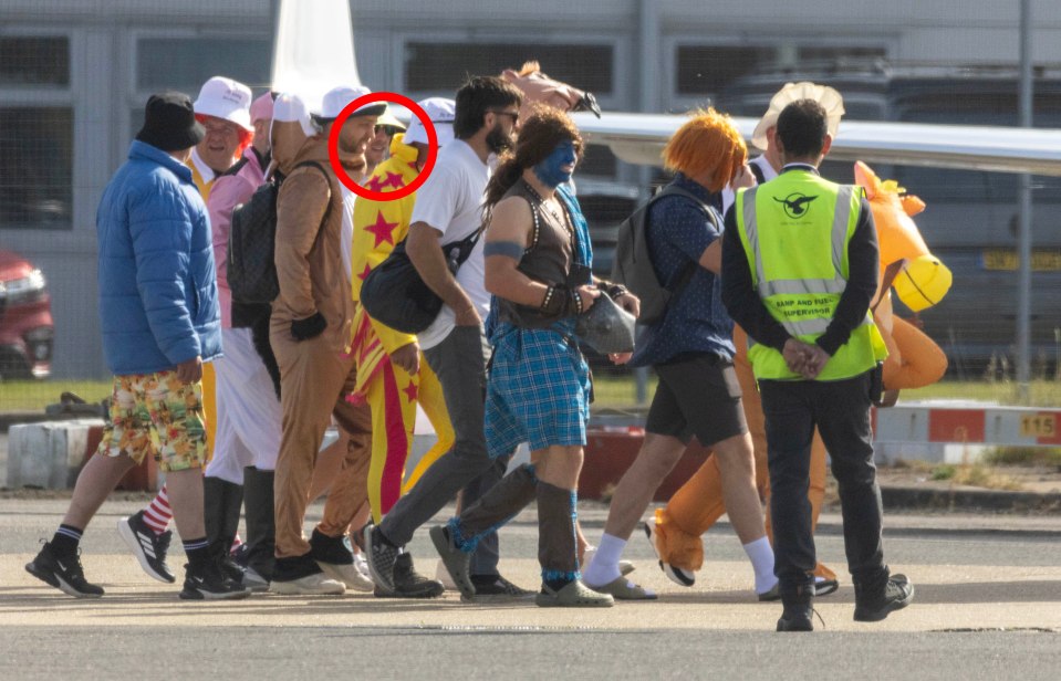 Group of men in various costumes boarding a private jet.