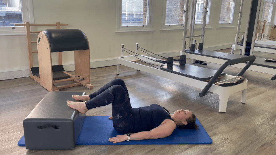 Woman doing Pilates leg exercise on reformer.