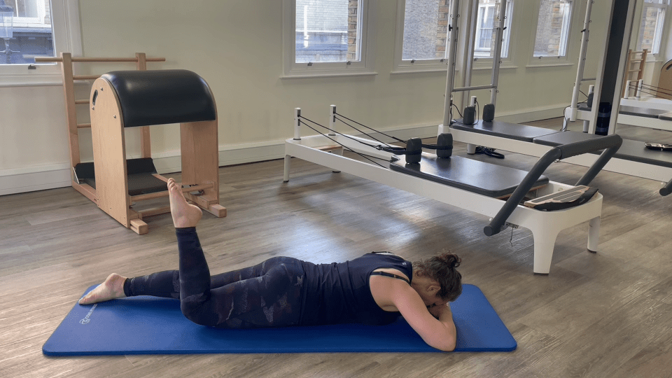 Woman performing a Pilates leg exercise.