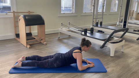 Woman performing a Pilates exercise on a mat.