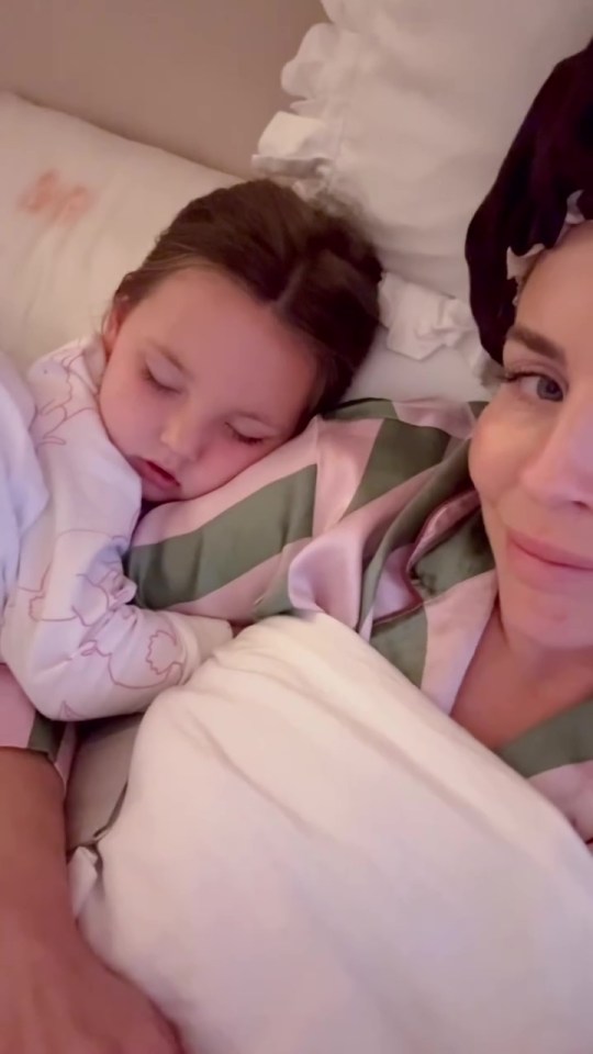 A mother and her young daughter sleeping together in bed.