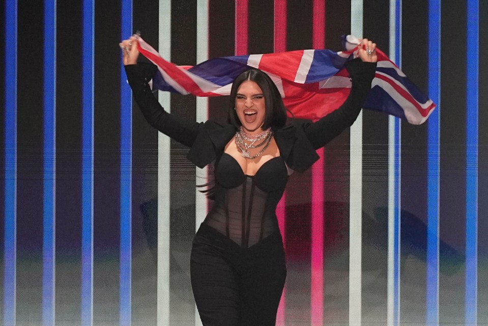 Mae Muller holding the UK flag at the Eurovision Song Contest.