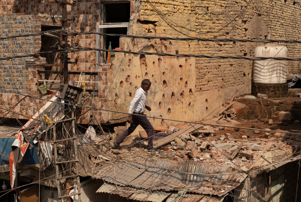 Man walking amidst debris on a damaged roof.
