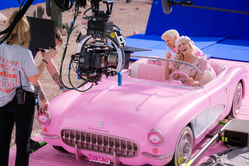 Margot Robbie and Ryan Gosling filming a scene in a pink car for the Barbie movie.