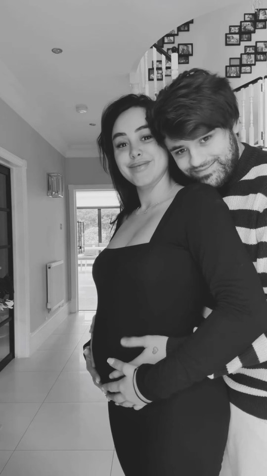 Black and white photo of a pregnant woman and a man embracing.