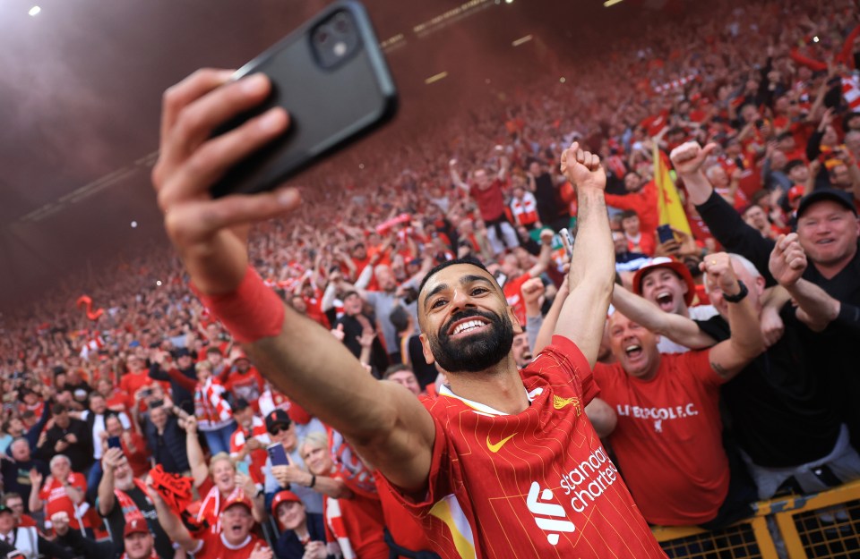 Mohamed Salah taking a selfie with jubilant Liverpool fans.