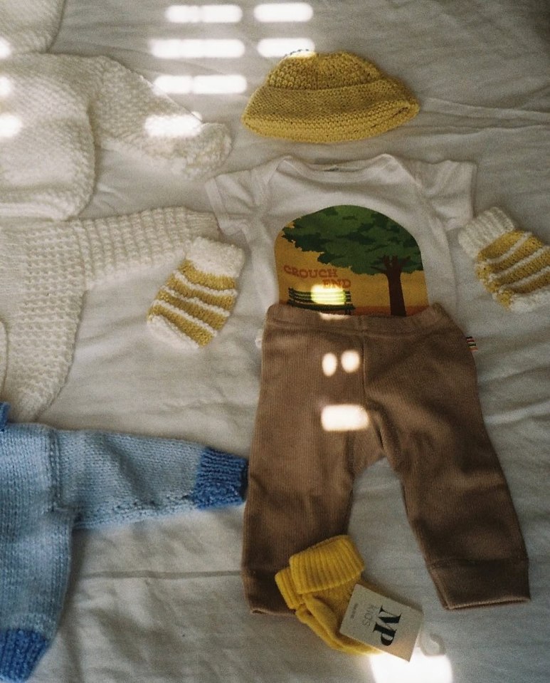 Baby clothes laid out on a bed.