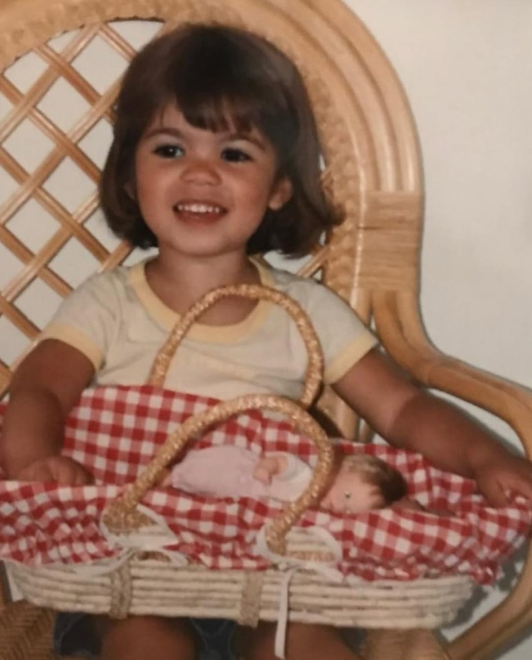 Young girl holding a doll in a basket.