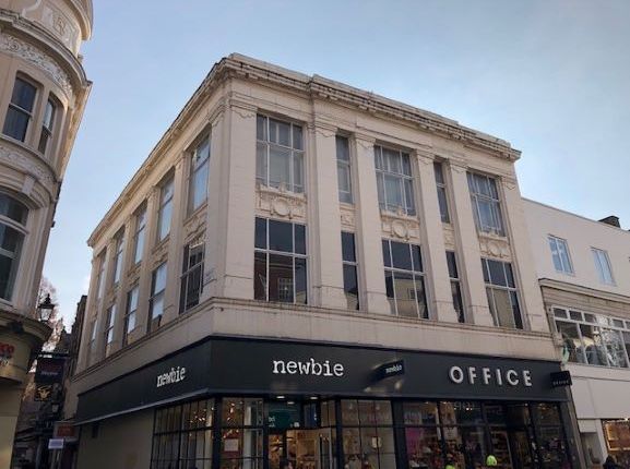 A tan building with large windows and a Newbie and Office storefront.