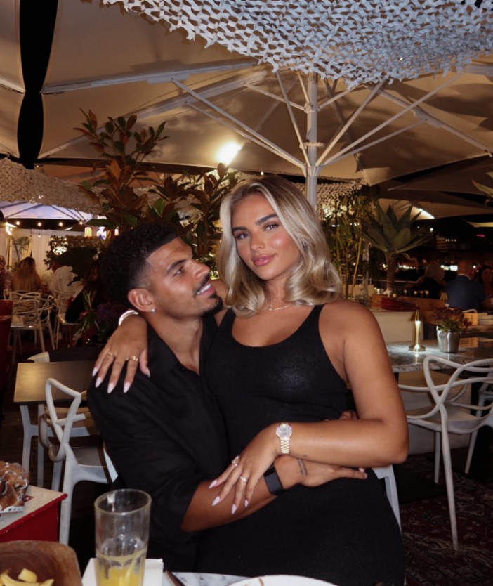 Couple sitting close together at an outdoor restaurant.