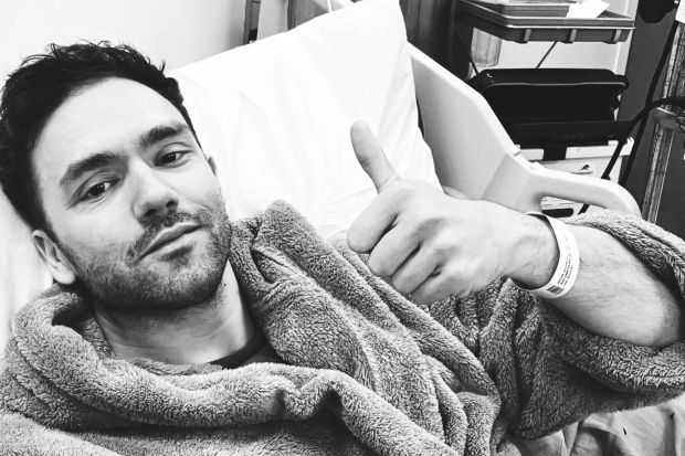 An image collage containing 1 images, Image 1 shows Black and white photo of a man in a hospital bed giving a thumbs up